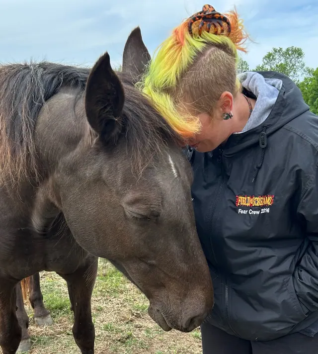 A quiet moment of connection beside a horse at the ranch
