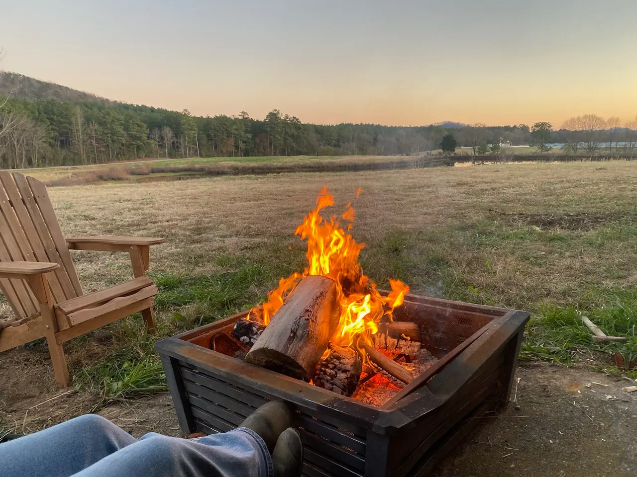 A warm evening fire beside a wooden chair overlooking the pasture