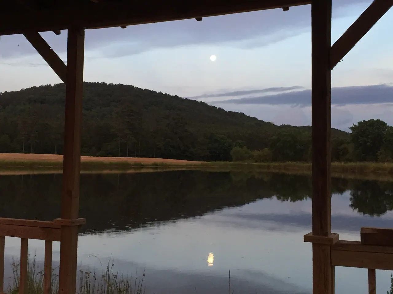 A quiet ranch lake reflecting wooded hills at dusk